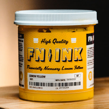 Close-up of a container of FN-INK in a bright lemon yellow color, labeled 'High Quality' and 'Financially Necessary.' The jar's design is bold and eye-catching, emphasizing the product's vibrant hue and suitability for professional screen printing projects.